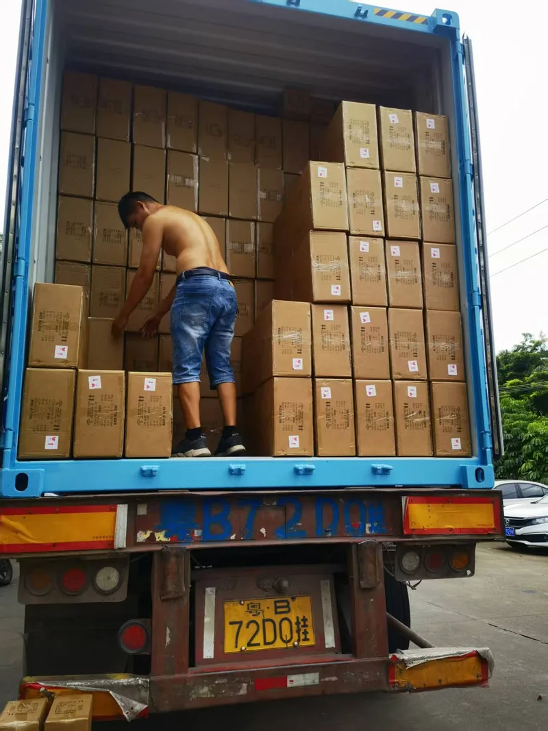 工人在蓝色集装箱波纹内壁旁码放纸箱